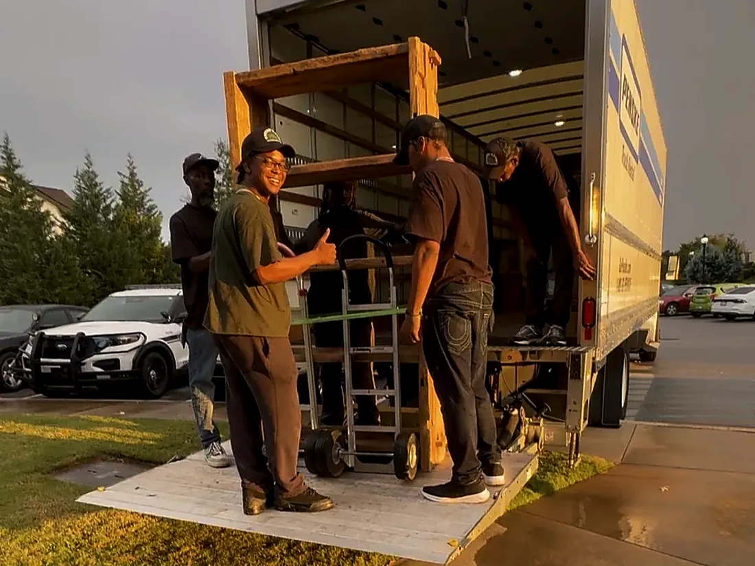 Carter's Moving crew loading furniture with a hand truck up a ramp
